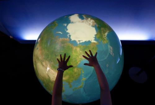 A visitor places her hands on a "Tangible Earth," a digital globe which real time global metrological data is fed through the Internet from about 300 places in the world, is displayed at an exhibition pavillion inside the media center for the G8 Hokkaido Toyako Summit in Rusustu town, on Japan's northern island of Hokkaido on July 6, 2008.