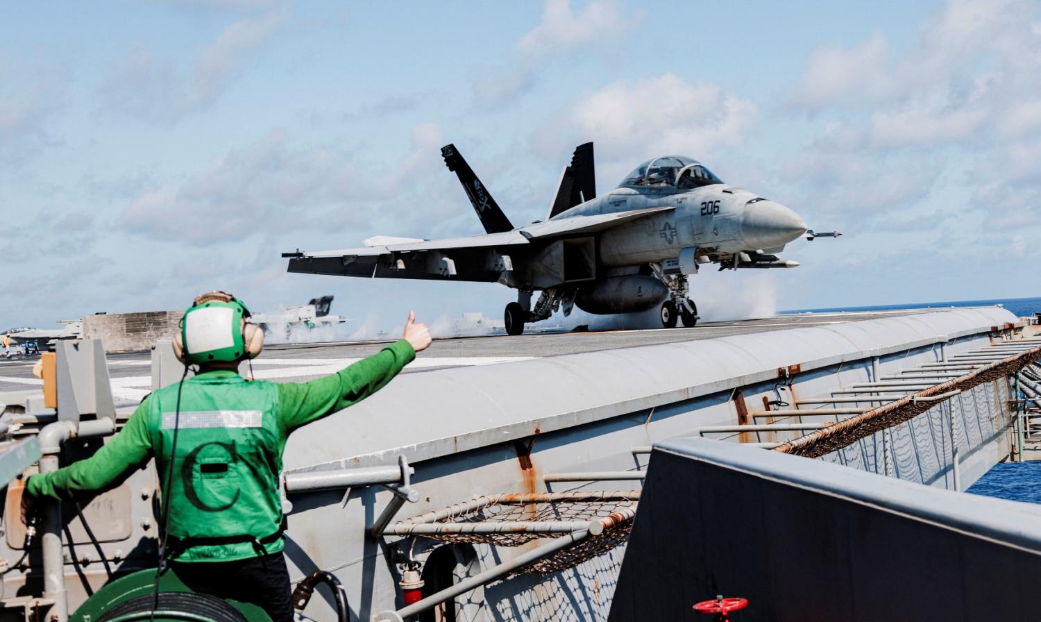 Handout photo dated May 2, 2024 shows Aviation Boatswain’s Mate (Launch/Recovery) Airman Tyler Cardamone, from Peak, Delaware, assigned to air department’s V-2 division, gives a thumbs up as an F/A-18F Super Hornet from Strike Fighter Squadron (VFA) 103 takes off from the Nimitz-class aircraft carrier USS George Washington (CVN 73) in the Atlantic Ocean.