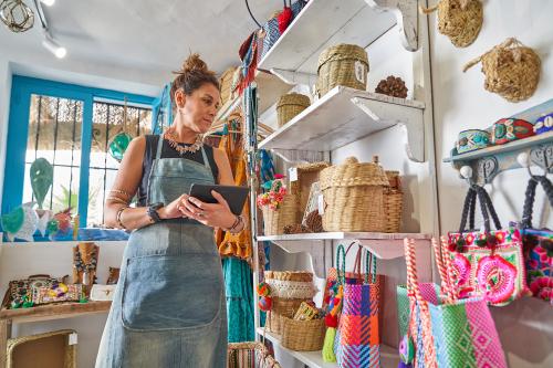 Female Hispanic souvenir shop owner taking inventory with digital tablet