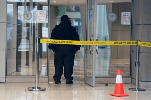 A security guard stands in a doorway behind yellow tape reading "Authorized access only."